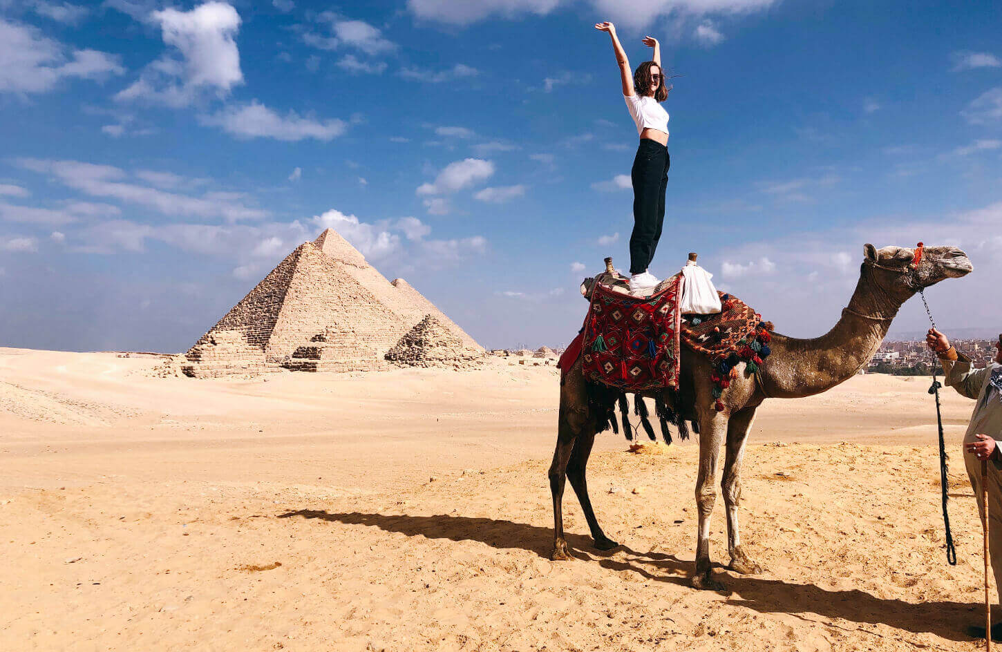 A female tourist standing on a camel