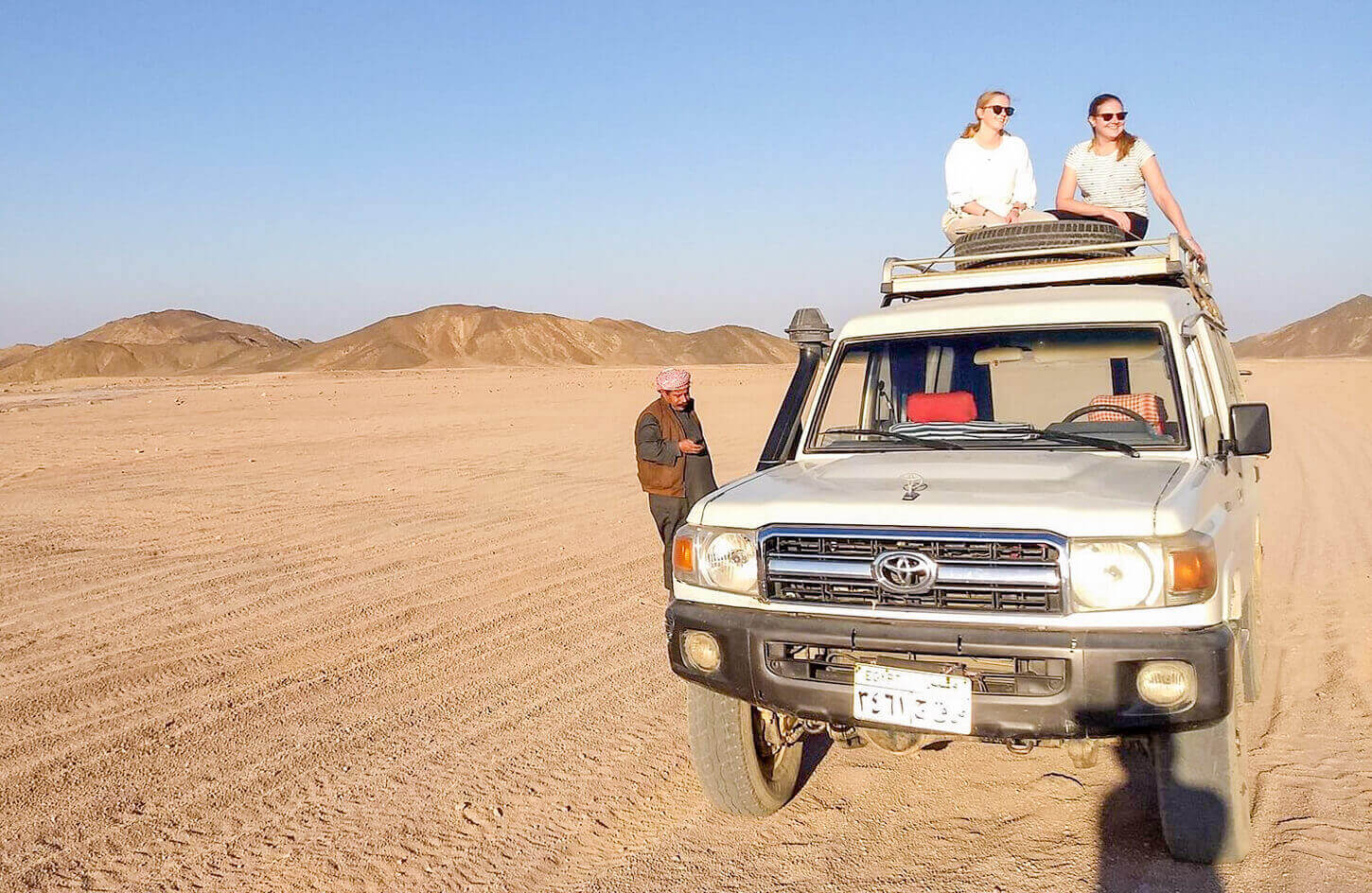 Two girls sitting on a four wheel drive vehicle from a safari trip