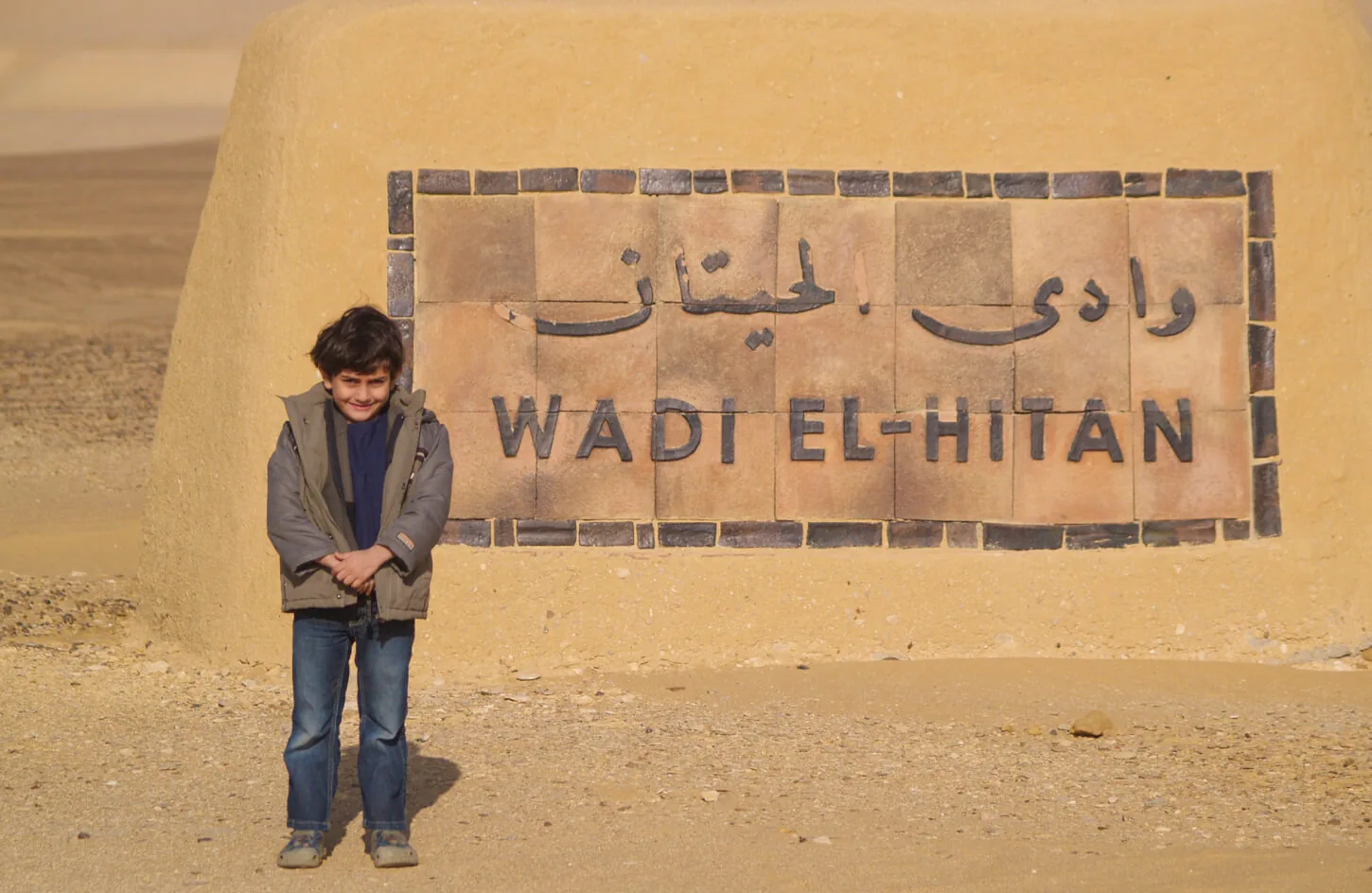 A child with a sign for the entrance to Wadi Al Hitan in Fayoum