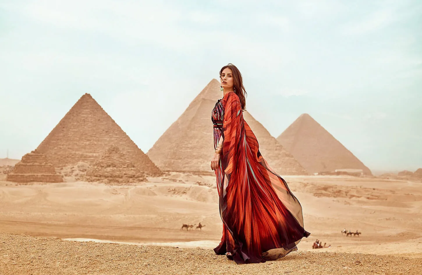 A girl wearing a red dress standing in front of the pyramids