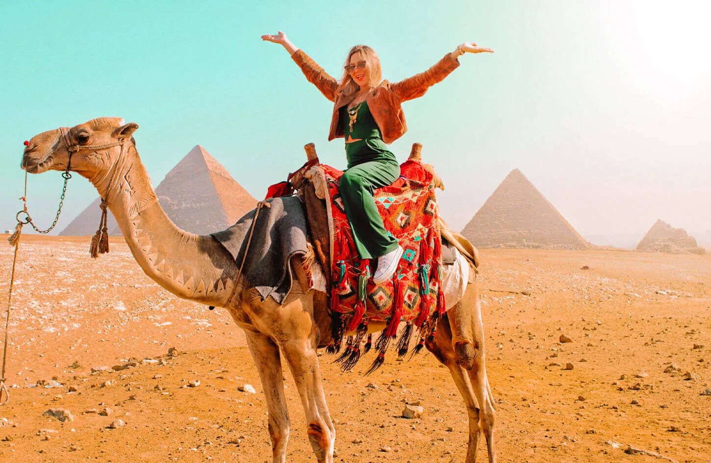 Visitor riding a camel in front of the Pyramids of Giza