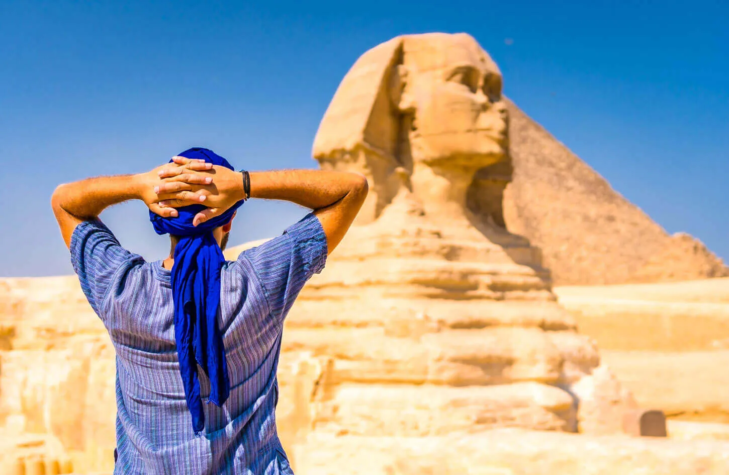 Young tourist wearing blue turban standing near great sphinx giza cairo egypt