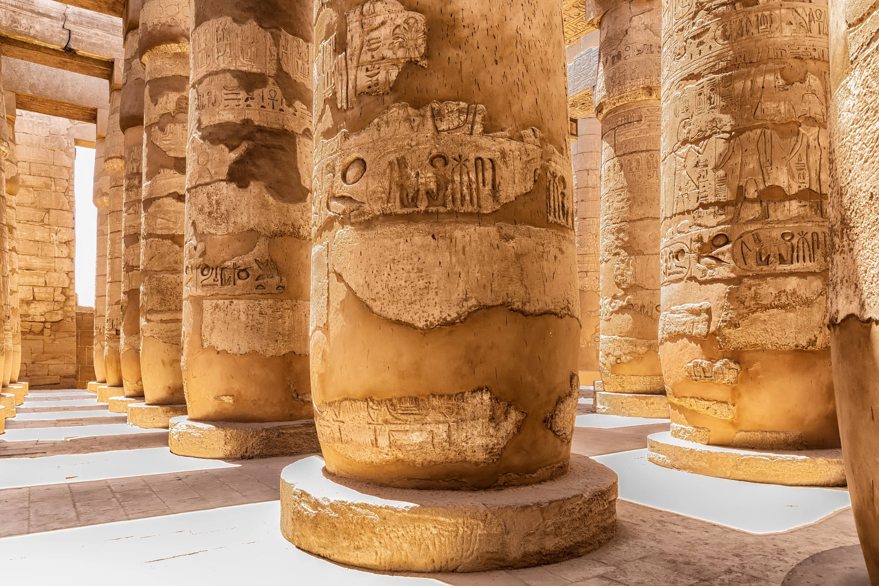 Sunlit sandstone columns carved with hieroglyphs at Karnak Temple